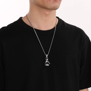 Gros plan d'un collier avec pendentif gant de boxe argenté sur un mannequin homme en t-shirt