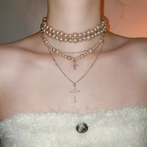 Close-up of triple-layer pearl necklace with sparkling rhinestone cross pendants