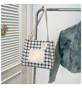 Detail of checkered canvas tote bag with leather pocket and cute white cat keychain