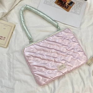 Close-up of pink quilted laptop bag with bow pattern and light green padded handle