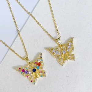Detail of gold butterfly pendant necklaces with vibrant colorful zircons on white background