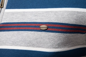 Macro detail of striped knit sweater featuring a metal zipper and branded metal plaque