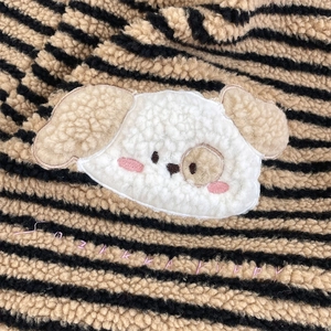 Detailed close-up of striped sherpa fleece texture with a cute puppy patch and pink embroidery