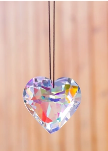 Close-up of heart-shaped crystal suncatcher pendant reflecting rainbow light on a string