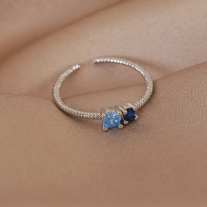 Close-up of silver spiral ring featuring light and dark blue zircon stones on silk