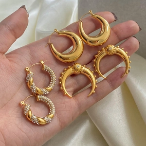 Close-up of gold stainless steel hoop earrings with pearls and crystals on white silk