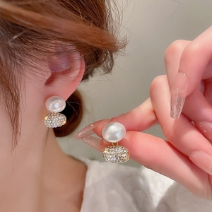 Close-up of pearl drop earrings featuring shimmering rhinestone pavé spheres