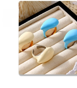 Detail von tropfenförmigen vergoldeten Ringen in Himmelblau und Creme auf Samttablett