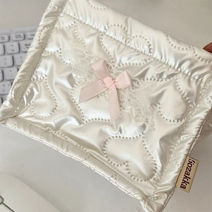Close-up of quilted white cosmetic bag with pink ribbon bow and delicate lace detail