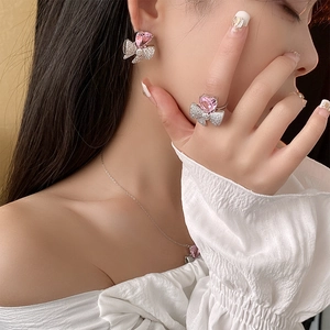 Détail de parure bijoux avec cœur rose en zircon et nœud incluant boucles et collier