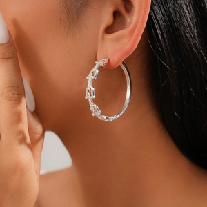 Macro shot of silver U-shaped chain earrings with cubic zirconia on a model ear