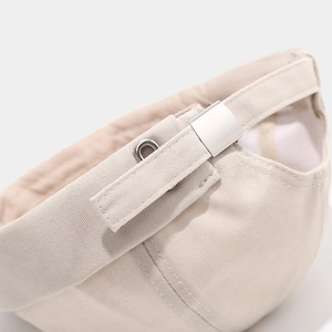 Detail of adjustable strap with silver metal buckle on a beige cotton docker cap
