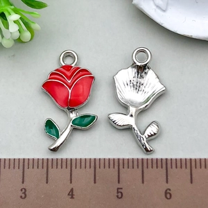 Detail view of red enamel rose charms with silver backing next to a measurement ruler