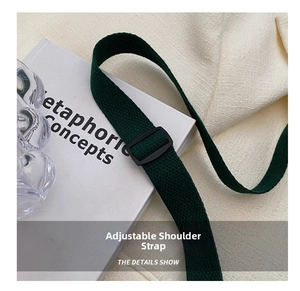 Detail of adjustable dark green canvas shoulder strap with black buckle on a tote bag