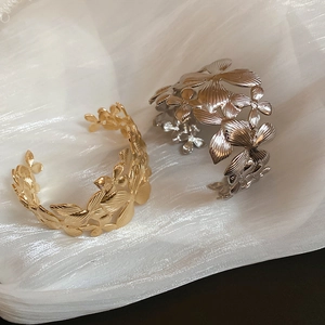 Vue rapprochée d'un large bracelet manchette ajouré avec motifs floraux or et argent