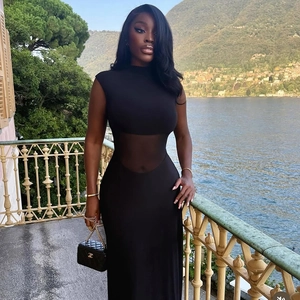 Sleeveless black maxi dress with sheer mesh waist and high collar in outdoor lake setting