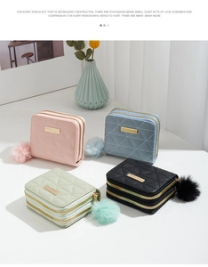 Close-up of quilted PU leather wallets in four colors with double zippers and fur pompom charm