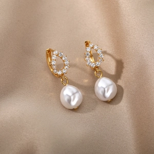 Detail of baroque pearl earrings with zircon inlay on champagne silk background