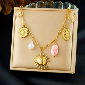 Detail of gold necklace with sun, moon, and pink heart pendants on jewelry box