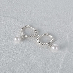 Macro shot of silver hoops with round white pearls on a minimalist grey background