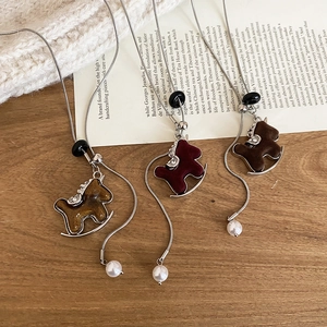 Detailed macro of flocked horse pendant necklaces with zircons on silver snake chains