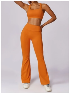 Detail shot of bright orange flared yoga pants and sports bra with high-stretch fabric