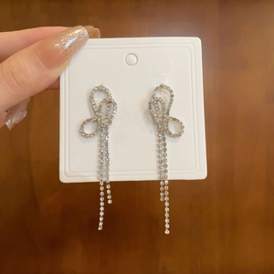 Close-up of silver tassel earrings with crystal butterfly bow and sparkling rhinestones