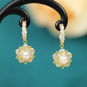 Detail view of gold flower earrings with white pearl and sparkling zircon inlays