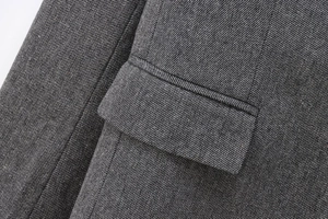 Detailed close-up of dark grey wool blend herringbone blazer pocket and fabric texture