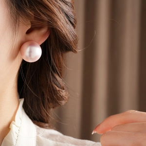 Macro close-up of a large pink pearl stud earring worn on the earlobe for a classic look