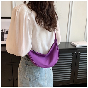 Model wearing a lightweight purple nylon crescent shoulder bag in a minimalist style