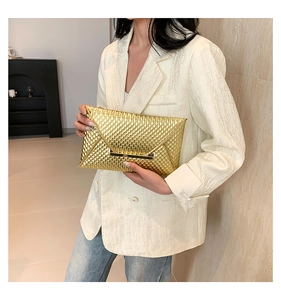Close-up of gold envelope clutch with honeycomb texture and metal bar closure