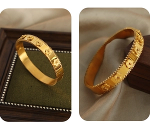Close-up of gold flower bangle with milgrain edges and vintage floral relief design