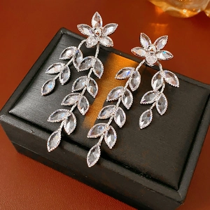Detail of silver drop earrings with crystal flower and leaf tassels on jewelry box