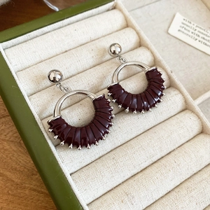 Detail of vintage silver hoop earrings with dark burgundy pleated texture in a jewelry box