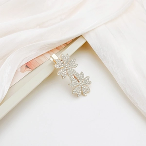 Close-up of gold cherry blossom hair clip with rhinestones on silk background