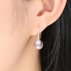 Detail view of pink pearl drop earring in s925 silver hook worn on a female ear