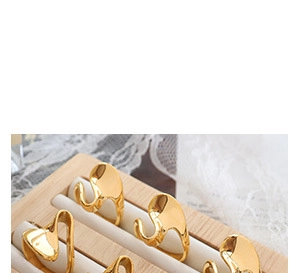 Abstract wave gold ring with irregular curved metal design on a wooden jewelry tray