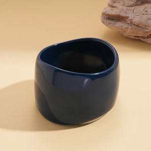Detailed view of dark blue glossy resin irregular geometric bangle with rock decor