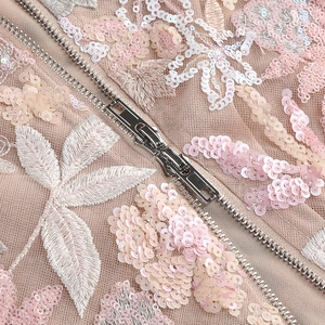 Macro view of sequin floral embroidery and silver double zipper on mesh party dress
