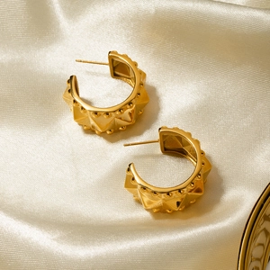 Detailed macro view of 18k gold-plated stainless steel rivet C-shape earrings on silk