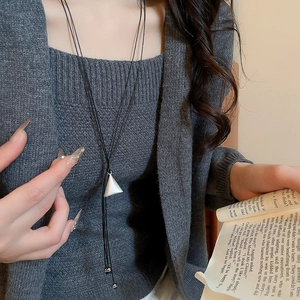 Close-up of minimalist black leather cord necklace with silver geometric triangle pendant