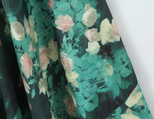 Détail macro du tissu vert foncé brillant avec des motifs de roses roses et blanches