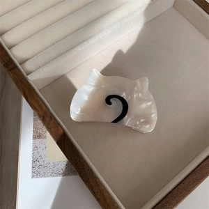 Macro view of cream acetate cat claw clip with pearl texture in a velvet jewelry box