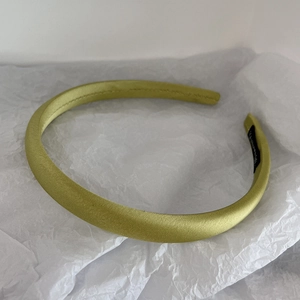 Detail of light yellow-green satin headband on white crinkled paper background