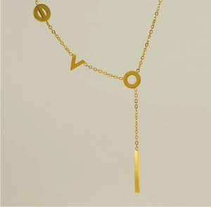 Détail du collier asymétrique en or 18k avec lettres V O et pendentif barre épuré