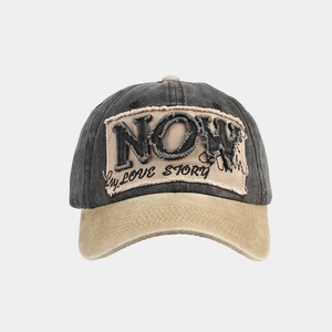 Makro-Detail der NOW-Stickerei und Love-Story-Patch auf Retro-Wasch-Baseballkappe