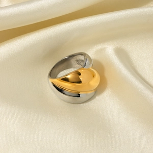 Macro detail of two-tone gold and silver minimalist ring on smooth silk fabric