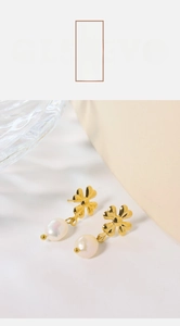 Detailed close-up of clover earrings with gold metal and white iridescent oval pearls