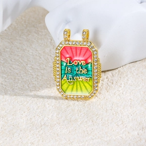 Macro detail of gold-plated Tarot pendant with zircon frame and enamel Love is the Answer text
